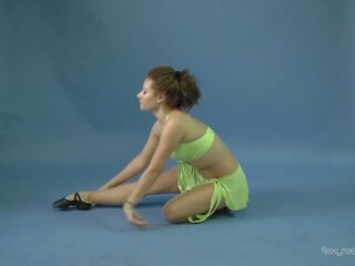 Klocka mila gimnasterka spridning henne benen och göra yoga exercises